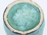 a close up of a green vase on a white surface