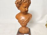 deux statues représentant un garçon aux cheveux bouclés, posées sur un socle en bois
