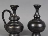 une paire de vases noirs posés sur une surface grise