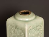 a green vase sitting on a table with a black wall in the background