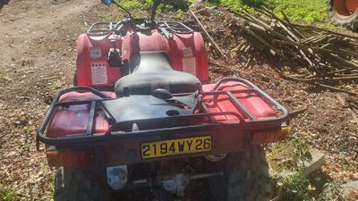 un quad rouge garé sur le bord d'un chemin de terre
