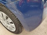 a close up of a blue car with a denting on it