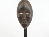 sculpture of a wooden face on a black metal stand
