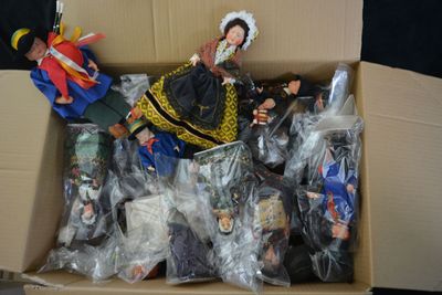 a cardboard box filled with dolls and other toys