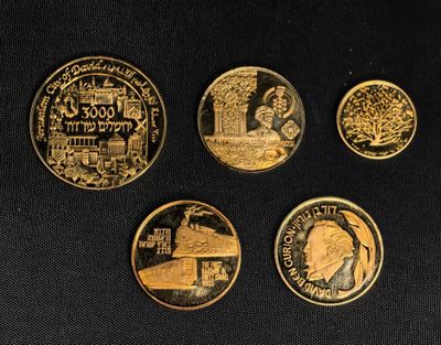 quatre pièces d'or présentant des motifs différents, posées sur un fond noir