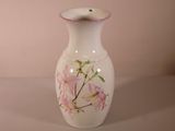 un vase blanc orné de fleurs roses peintes dessus