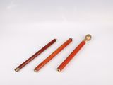 three red and gold colored pens sitting on top of a white surface