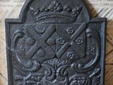 un vieil écran de cheminée en fonte surmonté d'une couronne