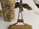 a brass statue of a bird on a stand