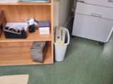 a room with a book shelf and a printer on the floor