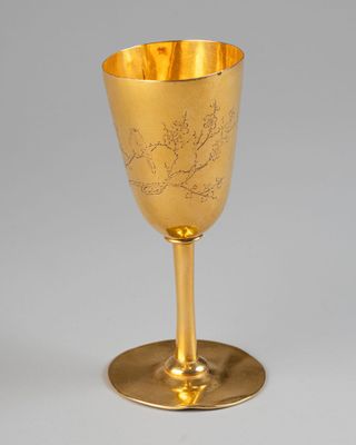 an antique gold goblet with a floral design on the stem
