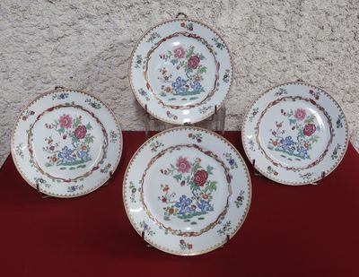 four plates with floral designs on them sitting on a red surface