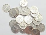 a pile of silver and silver coins on a white surface