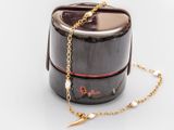 a black box with a gold chain and a pearl necklace on it