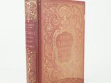 un vieux livre à la couverture rouge posé sur une surface blanche