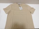 the shirt is tan and has a tag on it