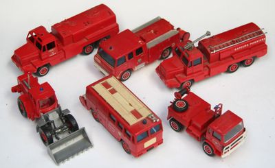 Plusieurs camions de pompiers miniatures sont alignés sur une surface blanche