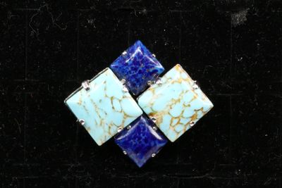 a close up of a blue and white broochle on a black surface