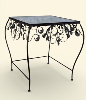 une table en fer avec un plateau en verre sur fond blanc