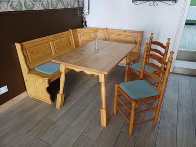une table en bois avec quatre chaises et un banc dans un coin