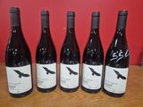 six bouteilles de vin sont alignées sur une table en bois