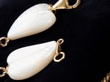 pair of white mother of pearl earrings on a black velvet cushion