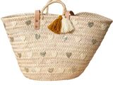 woven basket with tassels and leather handles on a white background