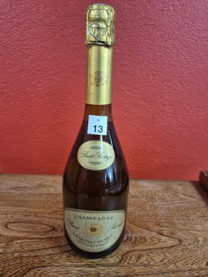 La bouteille de vin est posée sur une table en bois devant un mur rouge.