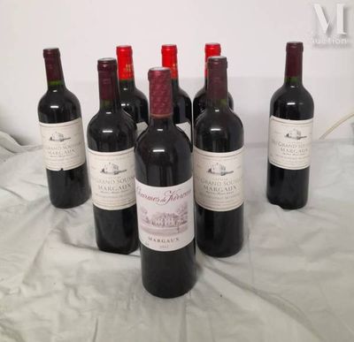 six bottles of red wine are lined up on a bed