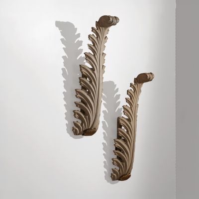 deux consoles en bois sculpté sur un mur blanc, avec des ombres