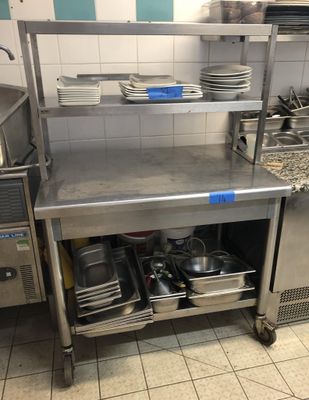 une cuisine avec un plan de travail en inox sur lequel sont posés tout un tas de casseroles et de poêles