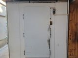 a white refrigerator in a garage with a wooden door