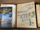 three books in a cardboard box on a table next to each other