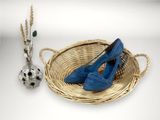un panier sur lequel sont posées une paire de chaussures bleues, à côté d'un vase