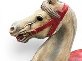 a wooden horse with a red harness on it ' s head
