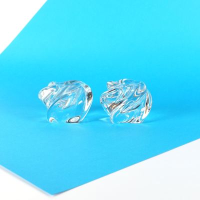 une paire de boucles d'oreilles en verre transparent sur fond bleu