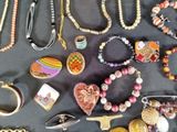 many different necklaces and bracelets laid out on a table