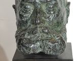 sculpture représentant une tête d'homme posée sur un socle en bois
