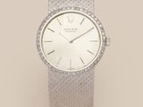 a lady ' s wrist watch with a white dial and a diamond bezel
