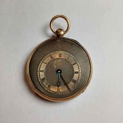 a gold pocket watch with roman numerals on the face