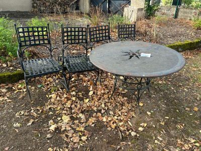 une photo représentant une table et quatre chaises dans un jardin