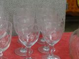 six wine glasses and a decanter on a table