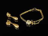 a gold bracelet and earring set with pearls on a black background