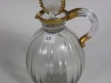 a glass pitcher with a gold handle on a white table