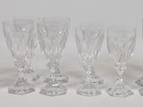 six clear glass goblets are lined up on a white surface