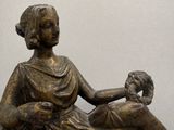 une statue en bronze d'une femme assise sur un rocher