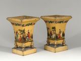 pair of yellow vases with painted scenes on them sitting on pedestals