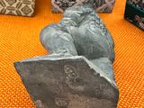 a small statue of a bird sitting on top of a rock