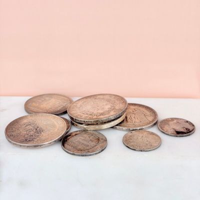several coins are sitting on a table next to a glass of water