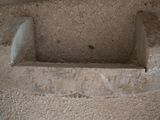 a toilet in the corner of a bathroom with a toilet paper dispenser